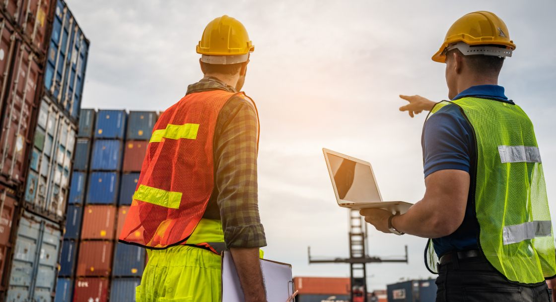 Dois trabalhadores de um condomínio logístico analisando containers modulares. 